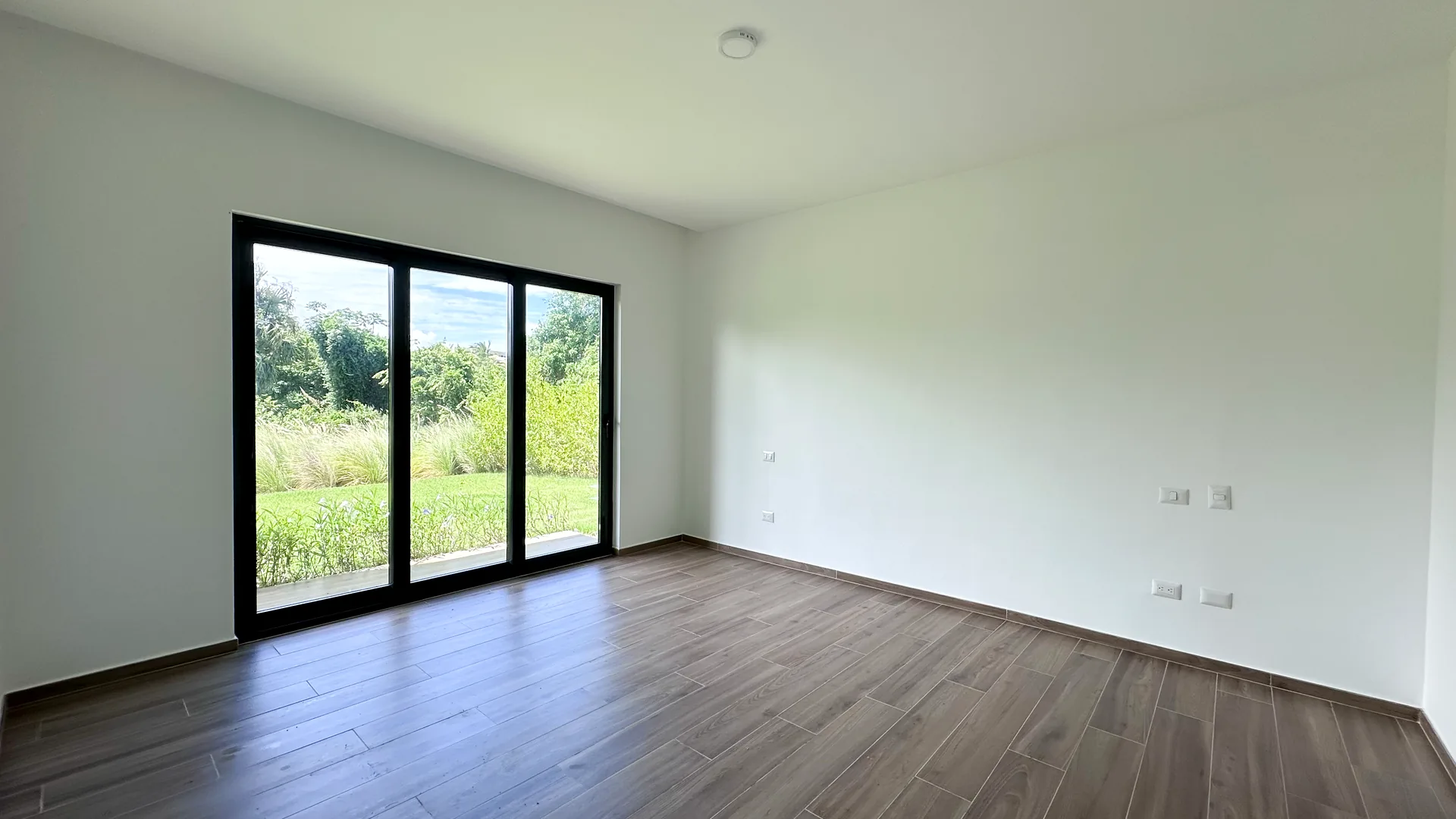 Cana Cove · Garden Residence A-101 — Master bedroom with garden-view sliding doors