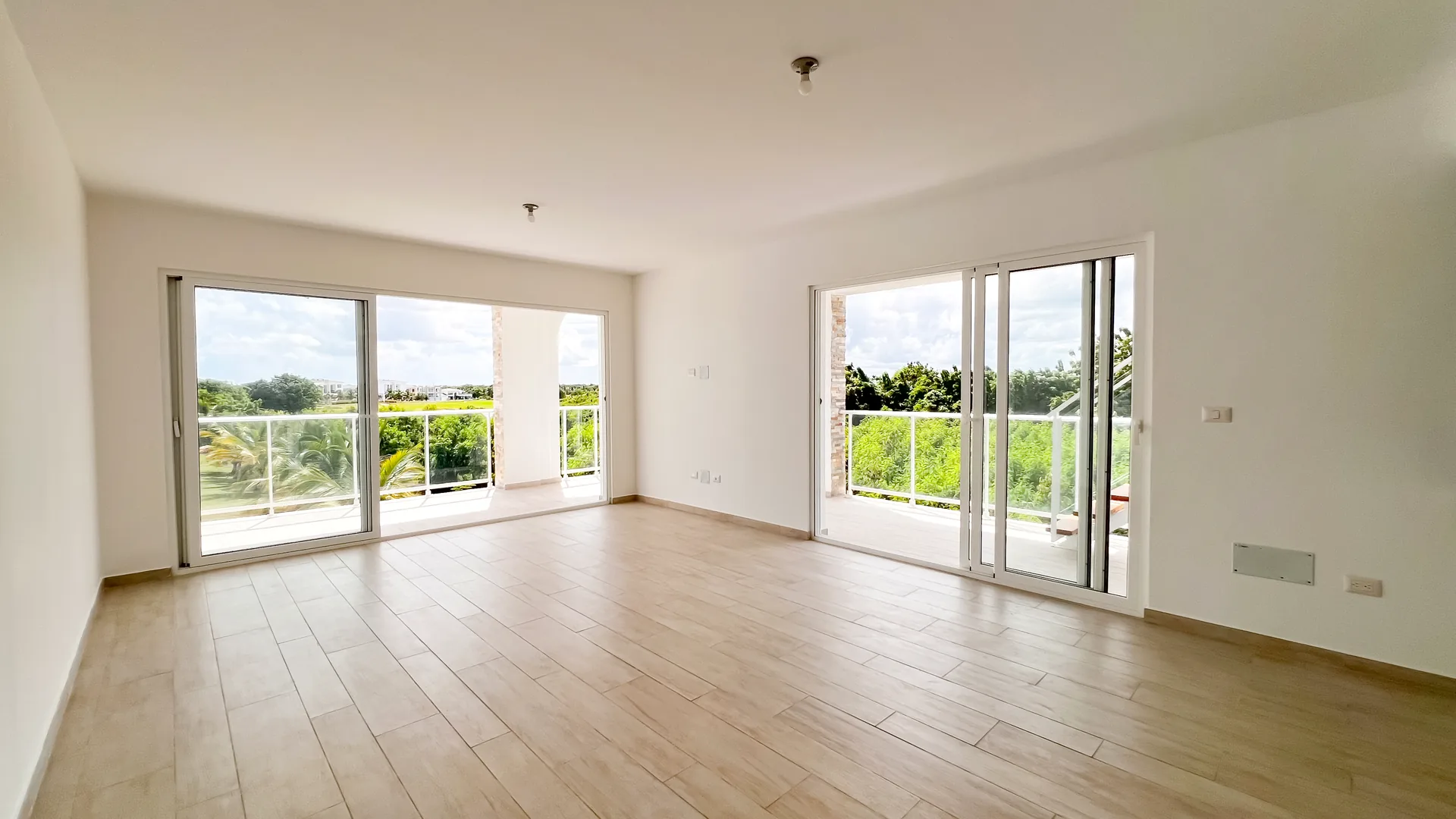 Cana Pearl · Rooftop Residence N-302 — Bright living-dining room with two balcony doors