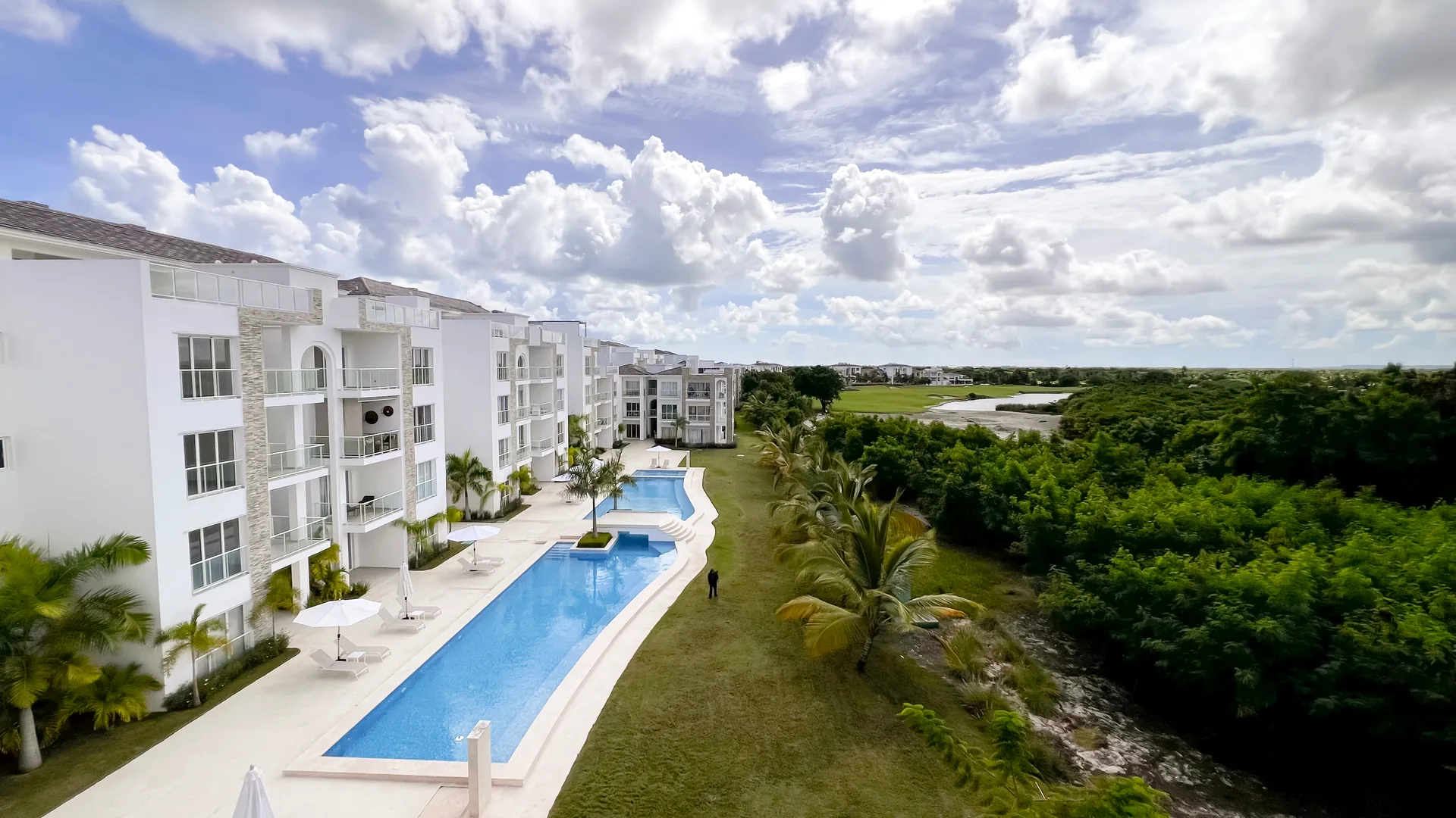 Cana Pearl · Rooftop Residence N-302 — Pool lined with palms beside the golf course